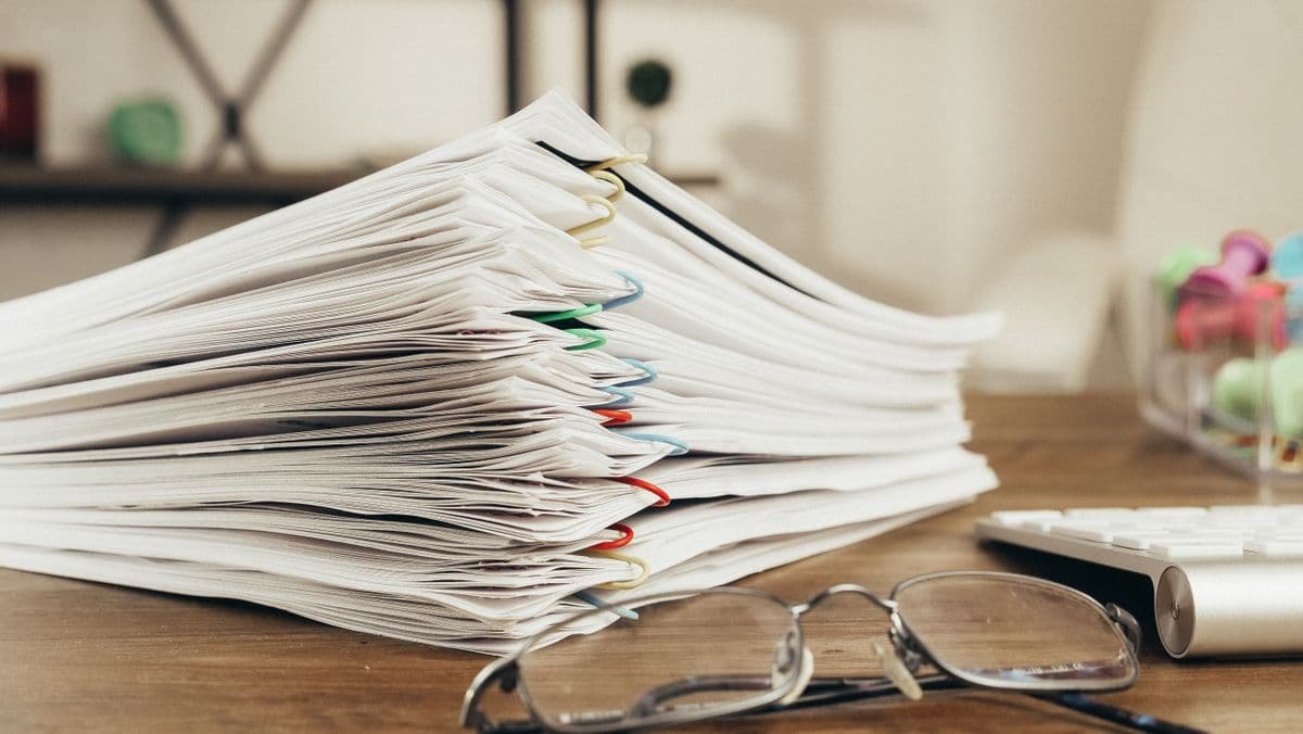 Documents agrafés posés sur une surface claire, vus de près.