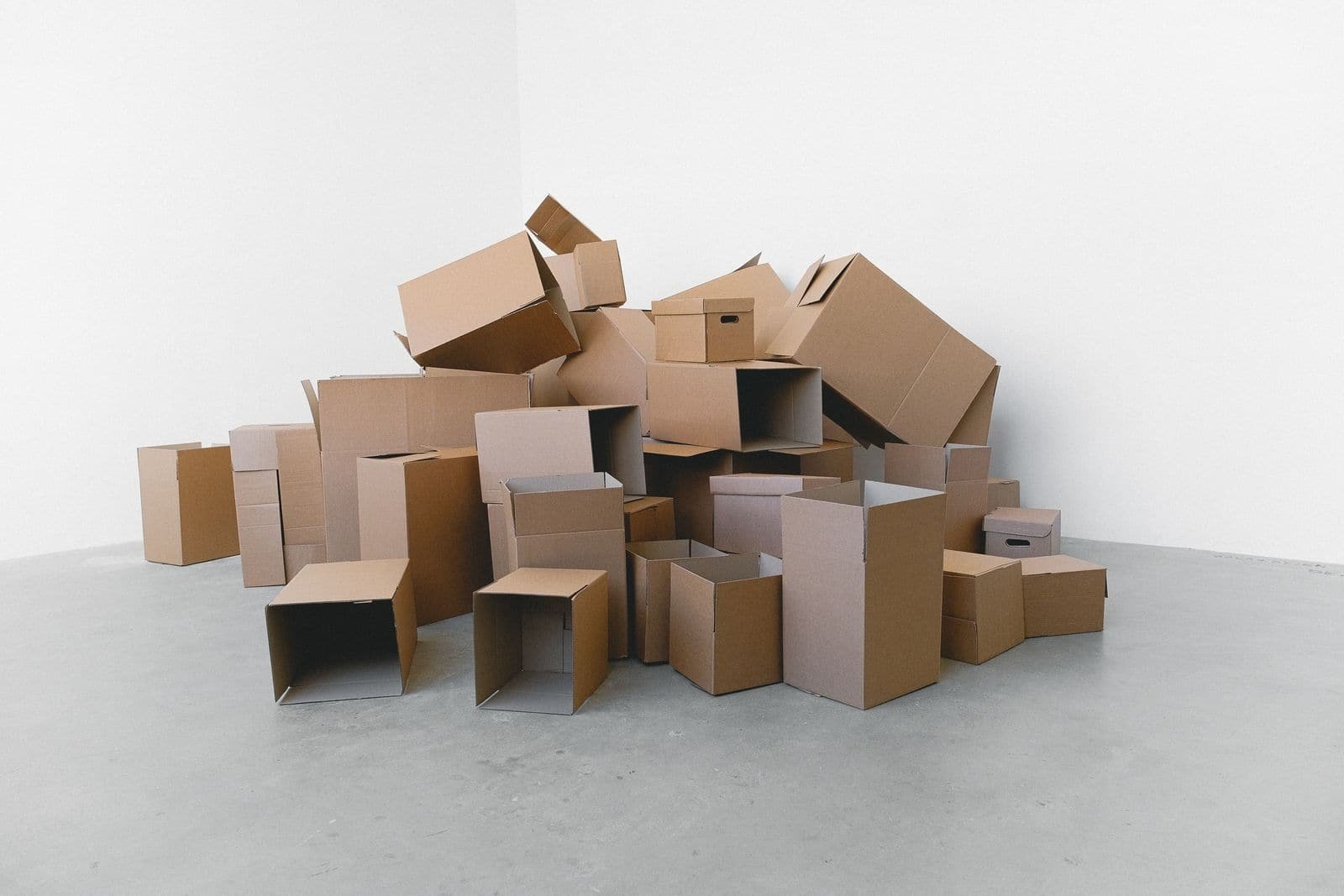 Pile de cartons posés au sol d'une pièce en cours de vidage.